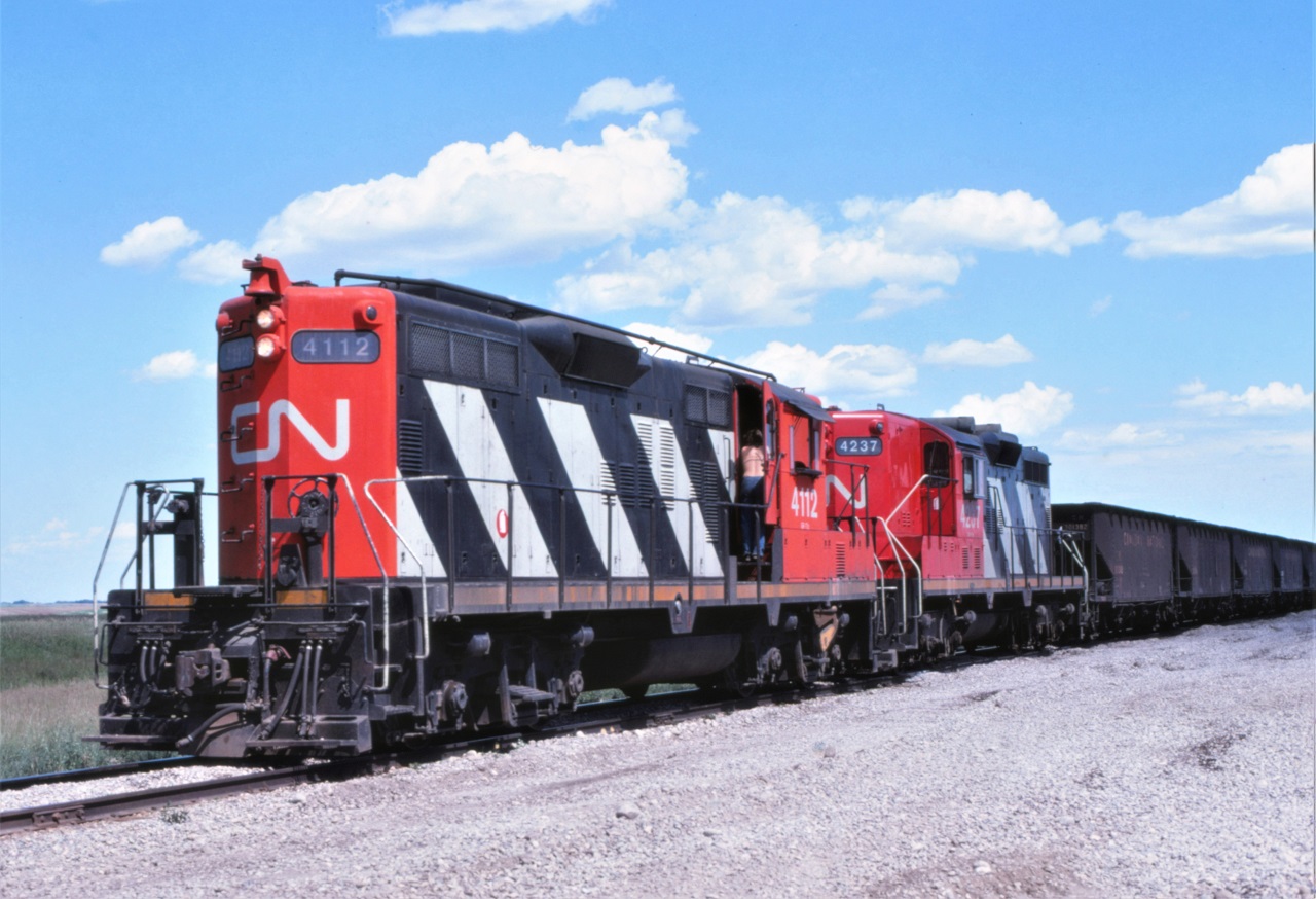 A CN work train unloads ballast along the Craik Subdivision near Chamberlain, Saskatchewan on a very hot afternoon.  A pair of relatively clean GP9s, 4112 and 4237, provide the power for the train.