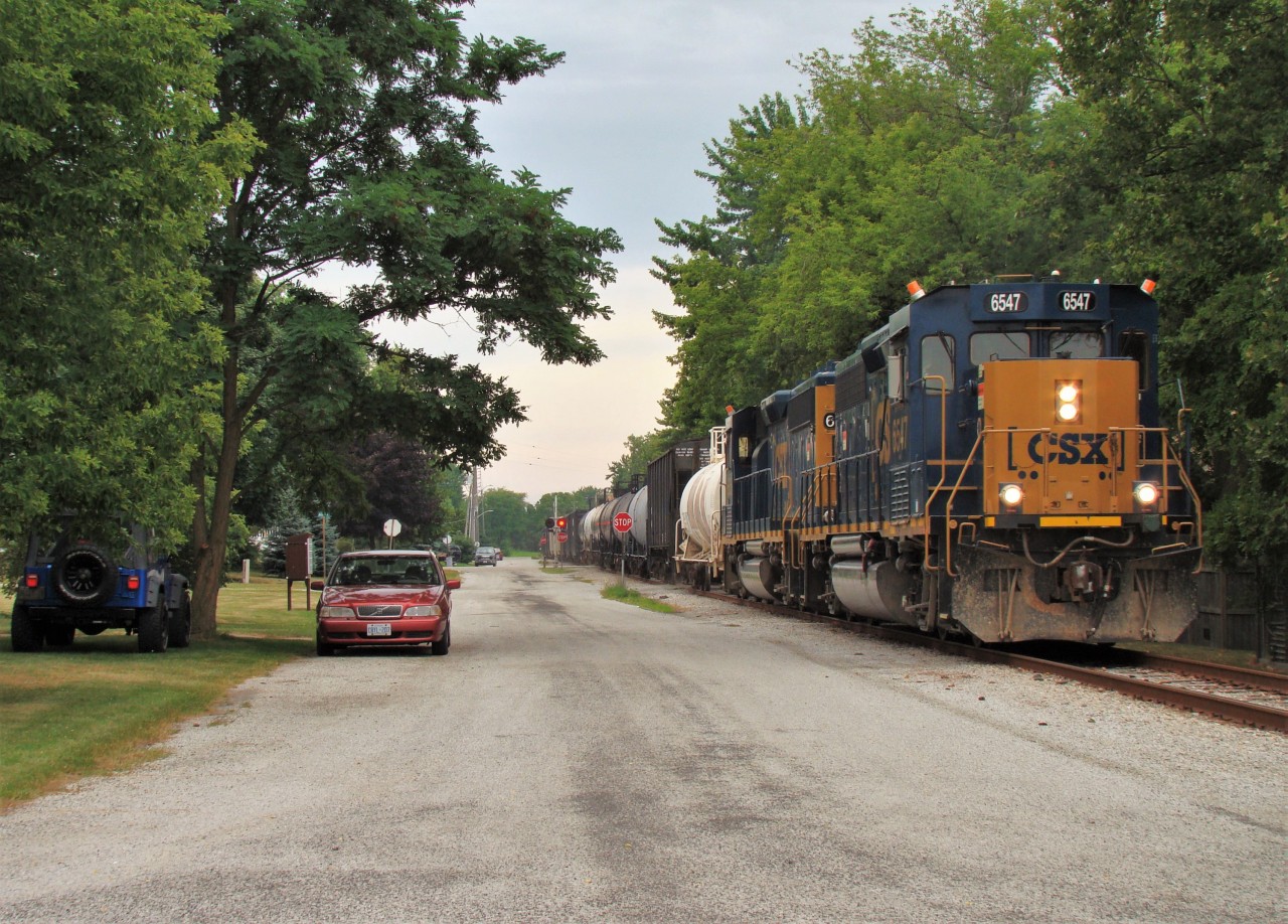 CSX 6547 and 6505 lead a 23 car local along Pulteney St. in Mooretown on their way back to Sarnia after switching Forge Hydrocarbons in Sombra and Lambton Generating in Courtright. The large Generating Station at Courtright is being dismantled and scrap is being shipped out by rail. CSX switches the place about 2-4 times a month and are currently running there Sunday afternoons.
