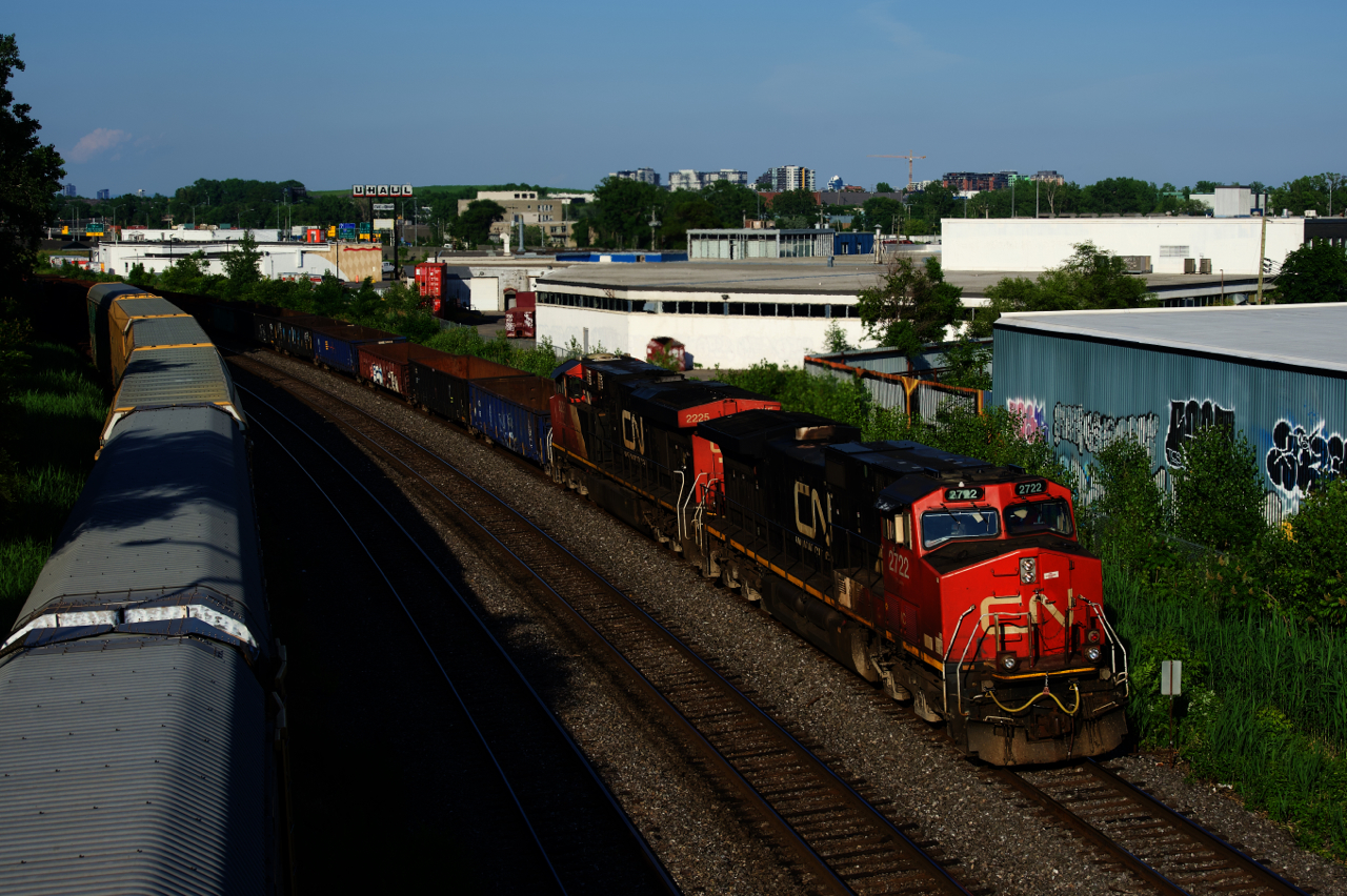 CN 321 has IC 2722 & CN 2225 for power as it passes cars parked on the Transfer Track of CN's Montreal Sub.
