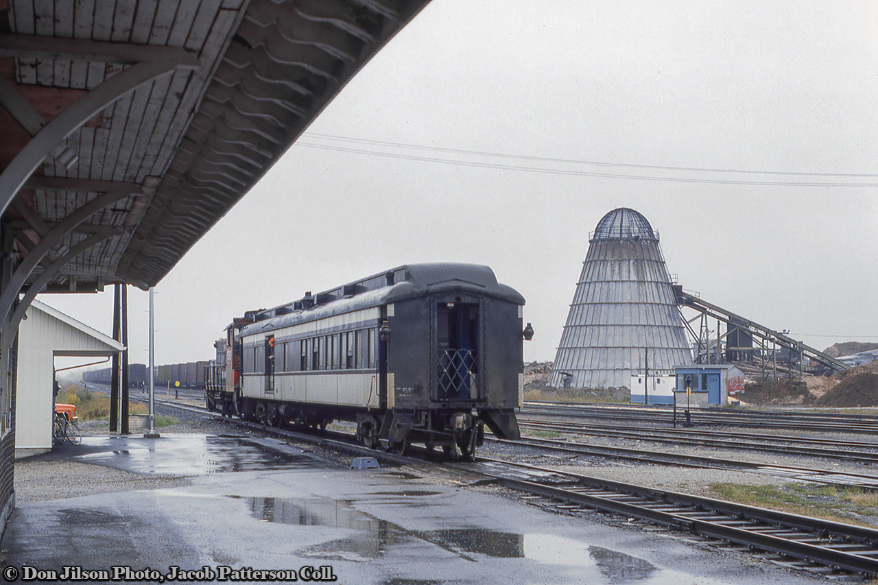 Almost the end, Part 2.  After moving about the yard (see part one here), mixed train 273 is now on the station track, and with the step box down, waits for passengers to board combine 7210.  Note the blue and gray shack at right which appears to be a scale house.Situated along the original National Transcontinental Railway line, built through the area in 1913, Hearst lies at the west end of the Kapuskasing Subdivision (Coachrane, mile 0 - Hearst, mile 129.1) and the east end of the Pagwa Subdivision (Hearst, mile 0 - Nakina, mile 144.1). Situated away from CN's mainline, the Kapuskasing and Pagwa Subs saw few upgrades and deferred maintenance over the years resulting in equipment restrictions on both lines. The Pagwa Sub specifically was still largely comprised of rails smaller than 80lb resulting in SW1200RS units being the heaviest permitted on the line, giving us the interesting scene here.Officially mixed trains 272/273 in the timetable, and operated by VIA Rail by the time of this photo, the trains no longer operated with freight in the consist as only one customer remained on the 144.1 mile line, Arthur Lecours Lumber Mill at Calstock (mile 22.7). It would typically be serviced by a job from Hearst. There is not long left for trains 272/273. With virtually no traffic on the line, attributed to the mainline further south, and deferred maintenance restricting load capacity, CN's request to abandon the Pagwa Sub west of Calstock would be approved, with the rails lifted in 1986. In August 1993, the Kapuskasing Sub and Pagwa Sub to Lecour's mill would be sold to the Ontario Northland Railway. Information per Chris van der Heide and his website, Algoma Central in HO Scale (more info on Hearst here).By this time, the original Hearst station had been retired but still stood with it's smaller replacement a few feet to the west (as seen in Arnold's linked image).CN 1392, built by GMD in 1960, would meet an untimely end on November 9, 1997 while assigned to the to the Shawinigan Falls Terminal Railway after being destroyed by a landslide. It would be chopped up onsite.More 1392Pups through Bayview, Dave Burroughs, 1967Departing Toronto Yard, First954, 1969Combine 7210, a Canadian Car & Foundry product of 1919, was assigned to mixed 272/273 for at least a decade before being reassigned to the "Muskeg Mixed" in Alberta:At Hearst 1976 with journal boxes, by Paul O'ShellAt Egremont, AB, July 1986 in VIA Rail colours, by Seth B.Don Jilson Photo, Jacob Patterson Collection slide.
