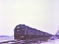 A dismal winter afternoon, even though this a color image might as well been black and white film. Train symbol MC-4 with a trio of F units and a U boat all elephant style running east on the double track CASO is about to bang over the diamond of the single track TH&B Dunnville sub. E&O tower was located at mile 30.5 on the Penn Central Canada Division CASO. A "Kodak Instamatic Moment" from long ago.