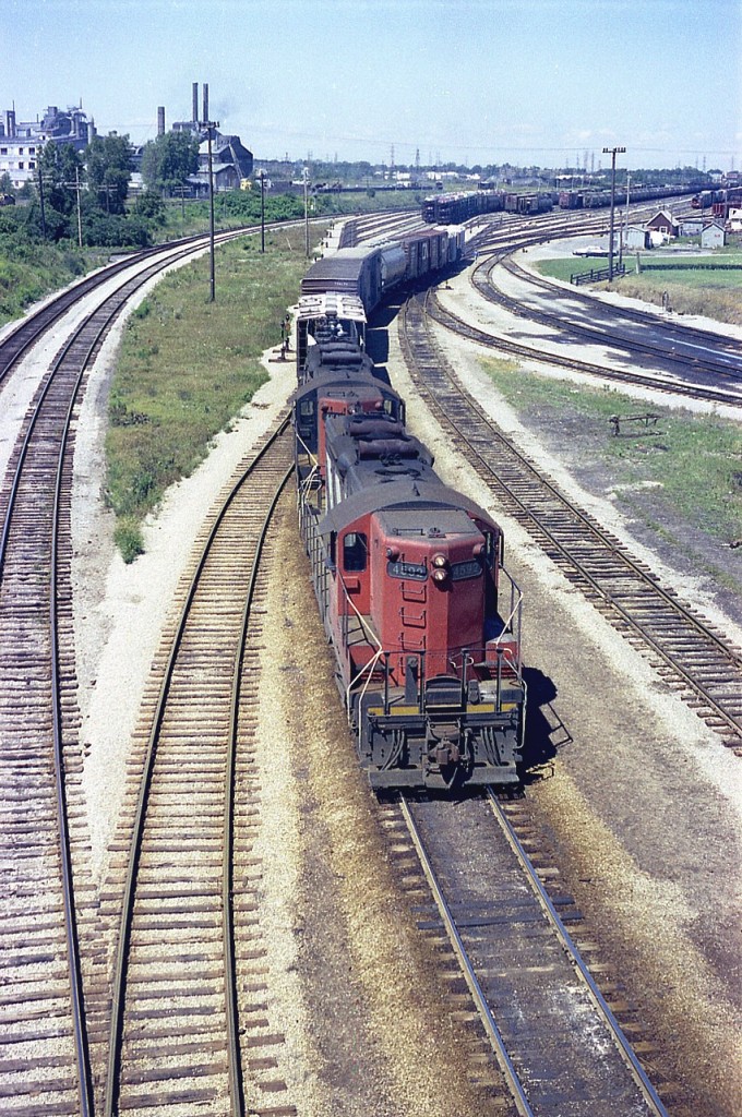 "Nothing to see Here".  Well, at least not any more.  The CN yard is gone. It is weeds. The obnoxious dangerous dust spewing Cyanamid plant in the background was torn down in 1992, after being a plague on the north-end of the city for many years. The two GP9s, 4589 and leader 4592 are no longer around.  This leaves us with pretty well nothing but the two track CN main line seen on the left. Most of what was once a notorious industry ( which produced calcium cyanide) and once was a rather large CN yard as seen in this photo is today nothing but wasteland, save for an arena built on part of the rejuvenated Cyanamid factory property on the far extreme left.
 So, the photo is old enough to be filed under history, having been taken from the Victoria Avenue overpass 45 years ago next month.