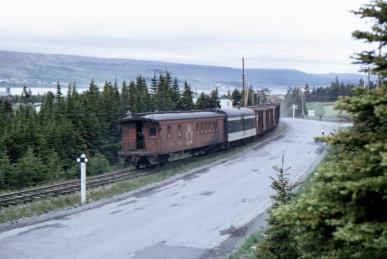 HEADING TO HARBOUR GRACE - Travelling with four University of Toronto friends - including the late James A. Brown - to celebrate Canada's Centennial by riding Newfoundland's endangered passenger train 'Caribou', John Freyseng of Ontario was able to capture some amazing narrow gauge images. Here he photographs a going away view of CN Train No. 212, the Carbonear Mixed, crossing Mt. Pleasant Road on the approach to the tiny station at Harbour Grace on June 22, 1967. Returning to St. John's, the trio of boxy G8's on the head end almost equal the revenue cars including baggage 1308 and combination coach/caboose 6009 and this unique train, including the diesels consisted of specially built 'Newfoundland' narrow gauge equipment. John's keen eye captured the unique railroading found only in Canada's tenth province in one of the oldest settlements in North America. Founded in 1517 by King Francis 1 of France, and headquarters of famous pirate Peter Easton, Amelia Earhart departed Harbour Grace not far from this location on May 20, 1932 to become the first woman to fly solo across the Atlantic. John would continue to chase and photograph this train until arrival at Brigus Junction and the mainline where he would board and experience the ride for himself as far as Holyrood. Harbour Grace would see its last mixed train on September 20, 1984 and following abandonment, the rails were taken up in 1987. More of 1967 John Freyseng photos can be seen in my upcoming TRAINS OF NEWFOUNDLAND, to be released by Flanker Press in both hard and softcover editions in September 2022.
