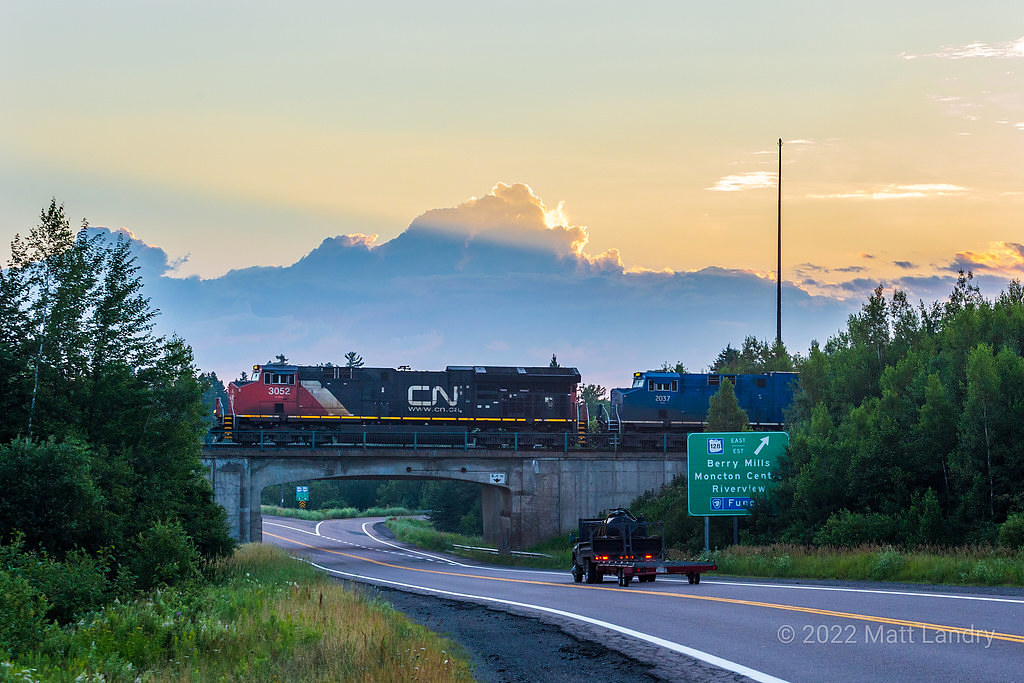 At sunrise, Q121 departs Moncton, approaching Berry Millls, New Brunswick. One of the few GECX engines that haven't been repainted yet trails.