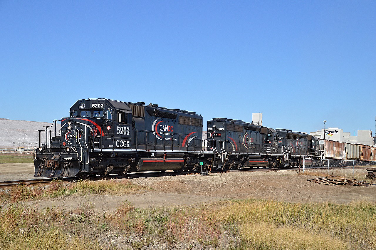 Cando 5203, 5303 and 5307 are seen working out front of the huge Mosaic Potash Mine near the village of Yarbo, which is northeast of Esterhazy, SK.  The underground mining had actually shut down 4 months earlier in June due to the increasing risk of flooding. The previously closed mine at Colonsay was currently being revamped and was to be open March 2022 with potash production to be going into full swing there. We were unaware of this situation until arriving at the Esterhazy mine and talking to one of the rail employees. So it was good to record this.