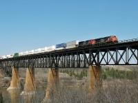 ES44DC CN 2259 and SD70M-2 CN 8964 lead an eastbound intermodal over the North Saskatchewan River at Clover Bar.