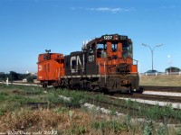 Running parallel to the Gardiner Expressway, CN SW1200RS 1237 trundles westbound at Mile 4.7 on CN's Oakville Sub on a "caboose hop" with wooden van 78547 on a local job (possibly heading to switch the nearby Ontario Food Terminal, or returning light power to Mimico Yard.
<br><br>
In the foreground is the switch to the former CN Humber Belt Line Spur, once the western branch of the Toronto Beltline Railway, but by this time a siding to the nearby Stelco Swansea Works at The Queensway & Windermere. The Toronto Beltline's "Humber Loop" once ran from here northward and eastward to West Toronto in the 1890's, but was cut down to small spurs when CN predecessor Grand Trunk Railway took over and began running freight. In the 1950's The Queensway was extended west and the spur (still serving one or two customers to the north) had diamonds and crossing protection installed for streetcars. This setup lasted until removal in the mid-60's. Around that time, Stelco expanded their property south over part of the line, and a small portion branching from the Oakville Sub here served as a siding for Stelco into the 1990's (the factory opened in 1885, closed in 1990, demolished for redevelopment in the early 2000's).
<br><br>
<i>Charles Houser photo (maybe), Dan Dell'Unto collection slide.</i>
