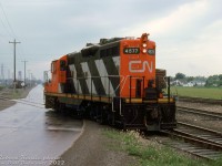 It's a gloomy, rainy day in Port Colborne as CN GP9 4577 works the east end of the yard at Nickel, crossing Durham Street heading back to the northern yard tracks along the Dunnville Sub mainline. According to a car control diagram, the yard tracks south of Durham St. that 4577 is coming back from are INCO-switched plant trackage, so the unit was likely interchanging some inbound INCO traffic. In the background, the towers of Lift Bridge 21 (Clarence St.) and 20 (CN Dunnville Sub) can be seen spanning the Welland Canal.
<br><br>
The Dunnville Sub was abandoned and removed by CN a few years later in the mid-80's, and a small portion here survives at the end of the CN Humberstone Spur (Yager to Nickel (Port Colborne)) to service the Vale Canada (former INCO) plant. The yard tracks were removed in the early 2000's, and a runaround remains.
<br><br>
<i>Robert Kentie photo, Dan Dell'Unto collection slide.</i>