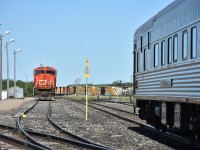 Assiniboine Jct. Mile 0.00 on CN's Assiniboine Sub. is a busy place this morning with CN 5626 sitting idle in the yard waiting for its next assignment, VIA 692 (VIA 8229 Chateau Viger sleeping car) holding the main in front of the Canora, SK station, and a moving CN freight in the background. Other interesting sights in the photo are a conductor walking back to the station, tall yard lighting poles, derails, restricted clearance sign, wind sock, station name sign, mile board, and some switch stands, several with unique targets.
