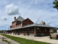 This mid-afternoon shot of VIA's Dauphin, MB station has a few passengers out on the platform stretching their legs during another stop on the 48 1/2 hour journey from Churchill to Winnipeg. Platform benches made from old railcar wheelsets dot this end of the station grounds, while a retired CN caboose (CN 79727) and a piece of maintenance equipment are on display at the opposite end. Dauphin station is home to the Dauphin Rail Museum. A view from the opposite end of the platform can be seen here;
http://www.railpictures.ca/?attachment_id=49621
