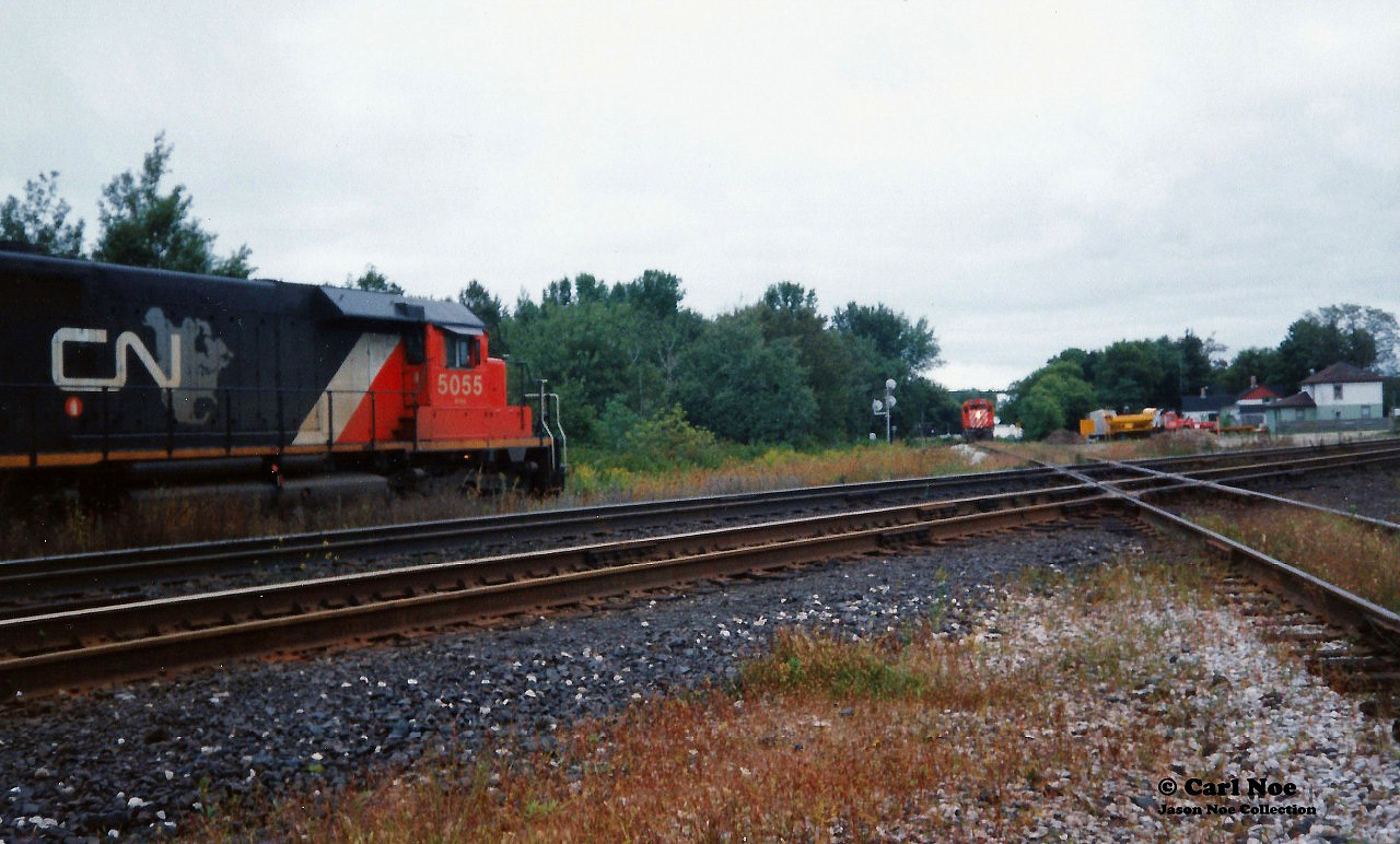 Back in September 1993 CN completed a large-scale bridge replacement west of Paris on the Dundas Subdivision. This resulted in CN rerouting trains not only on their Guelph Subdivision, but also detouring across Canadian Pacific’s Galt Subdivision for several days. In the west, the trains would begin their journey to the Galt Subdivision through the interchange track at Woodstock then onto the CP St. Thomas Subdivision for a short stretch before reaching the Galt mainline.

CN 392 is viewed waiting to proceed on this route with SD40’s 5055, 5029 and 5043 on September 15, 1993. CN 392 would actually wait here to meet a CP local seen approaching that was given priority as it headed to the Cami plant on the St. Thomas Subdivision.