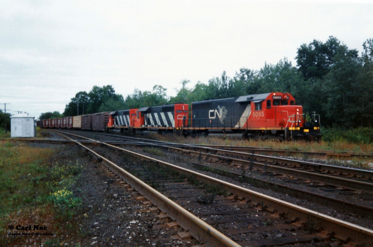 Back in September 1993 CN completed a large-scale bridge replacement west of Paris on the Dundas Subdivision. This resulted in CN rerouting trains not only on their Guelph Subdivision, but also detouring across Canadian Pacific’s Galt Subdivision for several days. In the west, the trains would begin their journey to the Galt Subdivision through the interchange track at Woodstock then onto the CP St. Thomas Subdivision for a short stretch before reaching the Galt mainline. 

CN 392 is viewed waiting to proceed on this route with SD40’s 5055, 5029 and 5043 on September 15, 1993. CN 392 would actually wait here to meet an approaching CP local that was given priority as it headed to the Cami plant on the St. Thomas Subdivision.