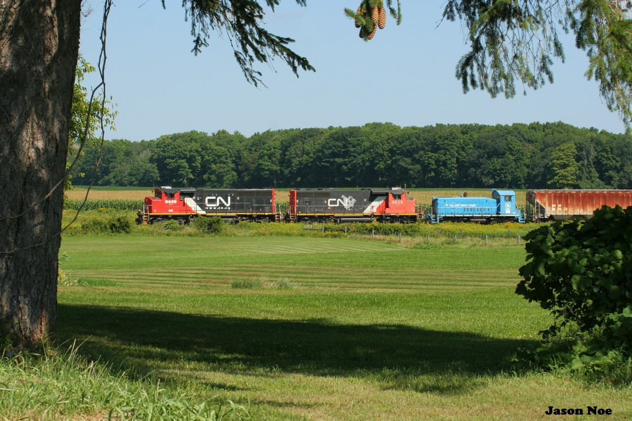 CN L568 with 9449 and 9639 as well as SSRX 911 in tow are just at the town limits as they approach Baden, Ontario heading westbound to Stratford on the Guelph Subdivision. The switcher was destined for the Roslin Enterprises facility, which is situated in the old Dana Corporation frame plant in St. Marys, Ontario.