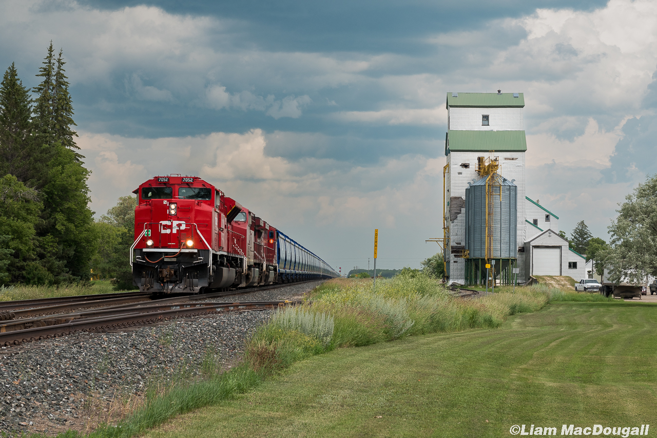 CP 7052 has a train of empty Potash as it heads west through Austin, MB. passing a nice old grain elevator which seems to still see some occasional use.