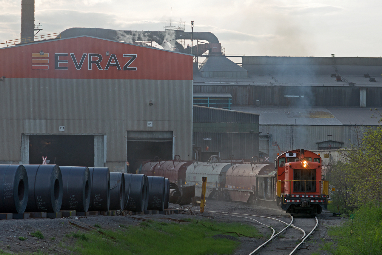 The often illusive SW900, Evraz #11 emerges from the roll shop with some freshly loaded coil cars on a hazy May evening.  Recent news states that the Russian based steel company (Evraz) has decided to sell off it's North American subsidiaries including this Regina location.  Evraz has owned the mill since 2008, before which it was owned and operated by IPSCO since the late 1950's. At one point the IPSCO was the largest employer in the city of Regina. It will be interesting to see what the future holds for Western Canada's largest steel mill.
