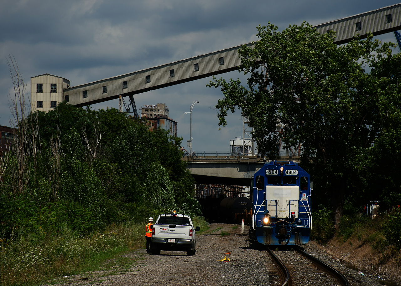 A foreman is waiting to put a derail back onto the CN Wharf Spur as soon as the Pointe St-Charles Switcher clears. It is heading from the Port of Montreal to its namesake yard with ex-GMTX CN 4904 leading.