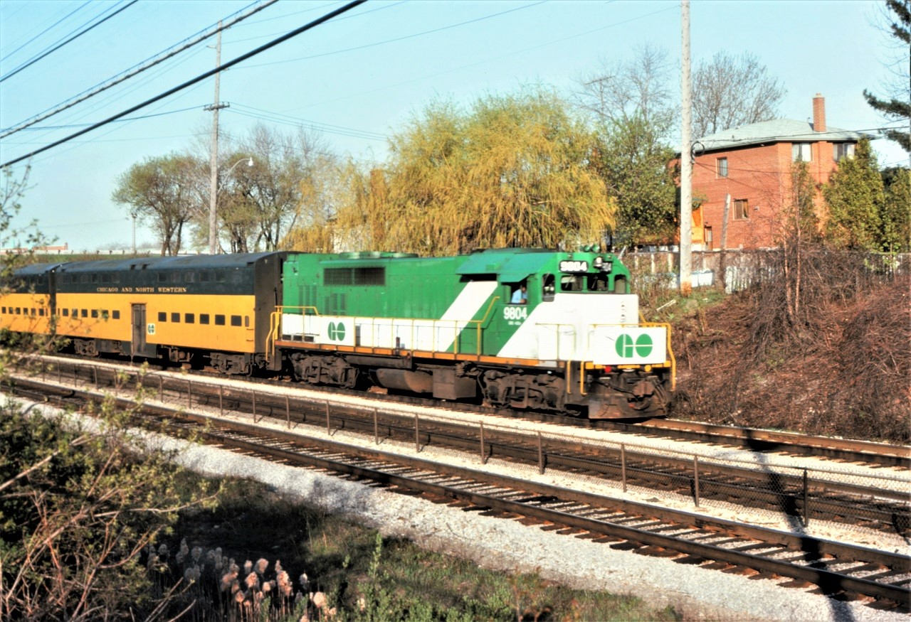 For a brief period in Apil 1976, GO Transit leased a set of 10 double deck commuter coaches from the Chicago and North Western Railroad.  The leased cars were numbered 1-5 and 11-15. In this photo, a westbound train with GO 9804 approaches the Long Branch GO station at speed.