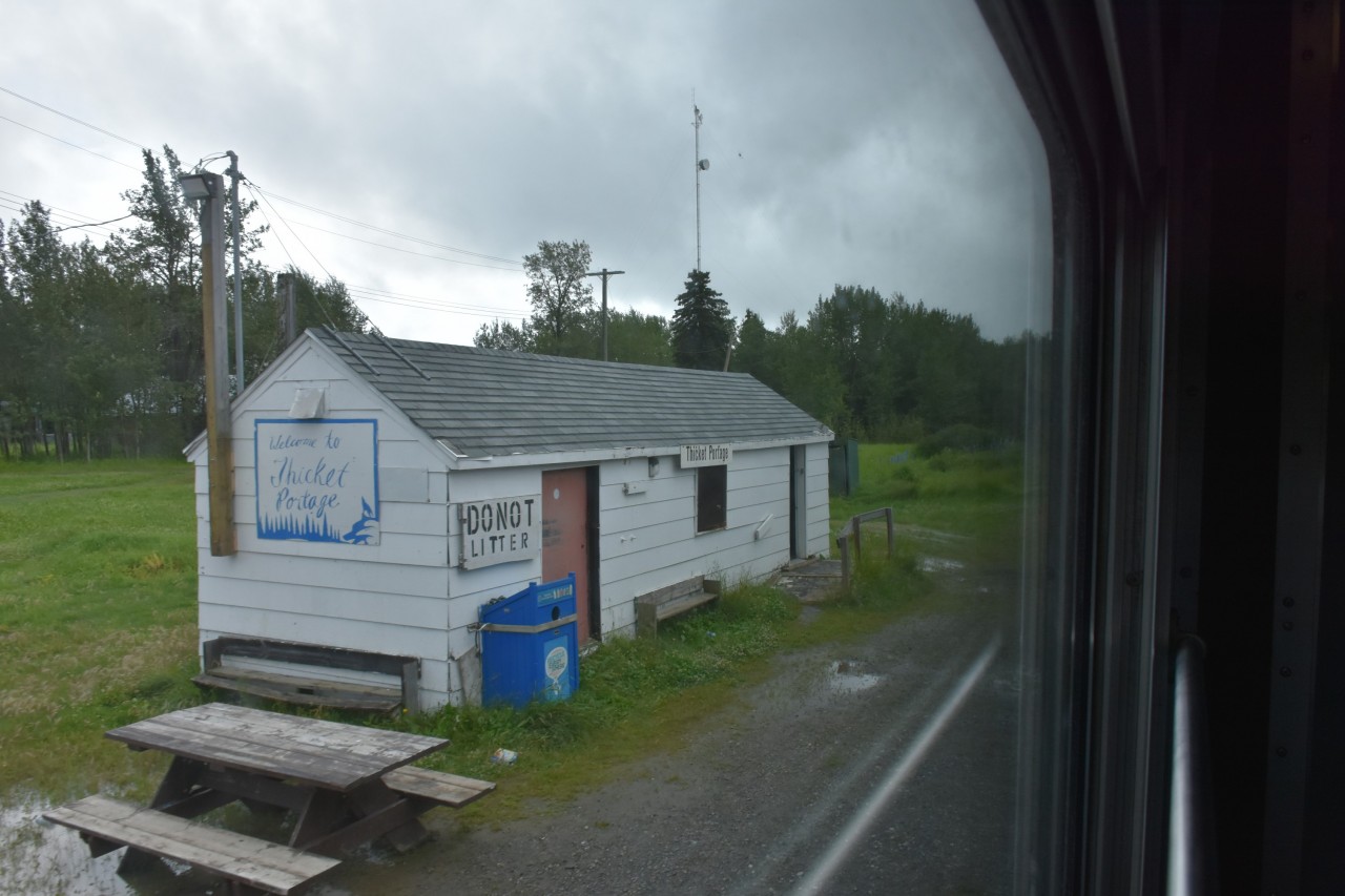 This shot isn't as pretty as others I've been posting, but it was my only opportunity to catch Thicket Portage railway station at Mile 184.3 on Hudson Bay Railway's Thicket Sub with my Nikon. This was on my return trip from Churchill, MB. and it is the best of several I snapped through the tinted, dirty, rain spotted glass of my bedroom D in sleeping car VIA 8229 Chateau Viger. This quaint building sits next to the tracks near the intersection of 1st Street & South Railway Avenue in Thicket Portage. On my journey up to Churchill I snapped a couple of photos with my iPhone and they show that this is quite the gathering place at train time.
A few facts about Thicket Portage;
Thicket Portage is a very remote community in northern Manitoba located on the Hudson Bay Railway.
The community receives passenger rail service at the Thicket Portage railway station.
The community has no all-weather road access.
The community is serviced by year round train access, local airport, and winter ice roads.