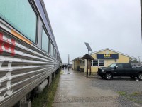 VIA #692 (Churchill to Winnipeg) is backed into the station at Thompson, MB on this cool, overcast, and drizzly August 5, 2022 noon hour. The step boxes are on the platform inviting people to detrain, but there are only VIA on-board, maintenance personnel, and me outside to do our respective tasks. The solar panel above the Thompson town map board struggles to do its job at the moment. If I was to turn around 180 degrees (which I did), the lens would capture VIA #693 parked about a car length behind the last car of #692. As this was a several hour station stop, a number of passengers ventured into the town of Thompson when the weather broke.