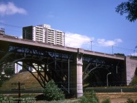 A train of brand new TTC H1 Subway cars crosses the Prince Edward Viaduct (aka the Bloor Viaduct) over the Don Valley, heading eastbound from <a href=http://www.railpictures.ca/?attachment_id=4666><b>Castle Frank</b></a> to Broadview Station on the recently opened Bloor-Danforth subway line. Streetcars previously <a href=http://www.railpictures.ca/?attachment_id=39089><b>crossed at deck level</b></a>, but when passenger volumes became too high, a new east-west subway line along Bloor Street and Danforth Avenue was built in the early-mid 1960's, opening in February 1966.<br><br>When the viaduct spanning the Don River was originally built for auto and streetcar traffic in the 1910's, it was built with an additional deck level below for a future rapid transit line. That deck went unused for five decades until the Bloor Danforth subway line was built in the 60's.<br><br>Visible below the bridge is the Don Valley Parkway under the right arch, along with <a href=http://www.railpictures.ca/?attachment_id=46919><b>CP's Don Branch</b></a> (Belleville Sub) under the same span (running along the retaining wall, note the silver signal cabinet box trackside). The codeline poles in the foreground are for <a href=http://www.railpictures.ca/?attachment_id=48665><b>CN's Bala Sub</b></a>, on the other side of the Don River.<br><br><i>John F. Bromley photo, Dan Dell'Unto collection slide.</i>