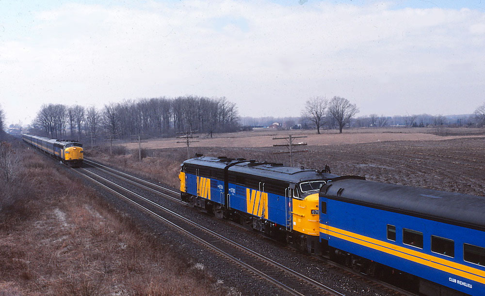The prospect of taking an action photo of a MLW-built cab unit would usually get the adrenalin flowing, but quite the contrary on this occasion. It is 31 March 1989, and the last day VIA FPAs can lead passenger trains in Canada. An overcast sky and faint drizzle only add to the melancholy mood. Westbound VIA Train #83 passes with a pair of Montreal-built beauties on the point. An eastbound counterpart is led by a pair of the competitor's cab units. In a few short hours, the curtain will be drawn on a disappearing railroad scene, but for a brief moment FPA4s #6764 and 6780 are center stage.