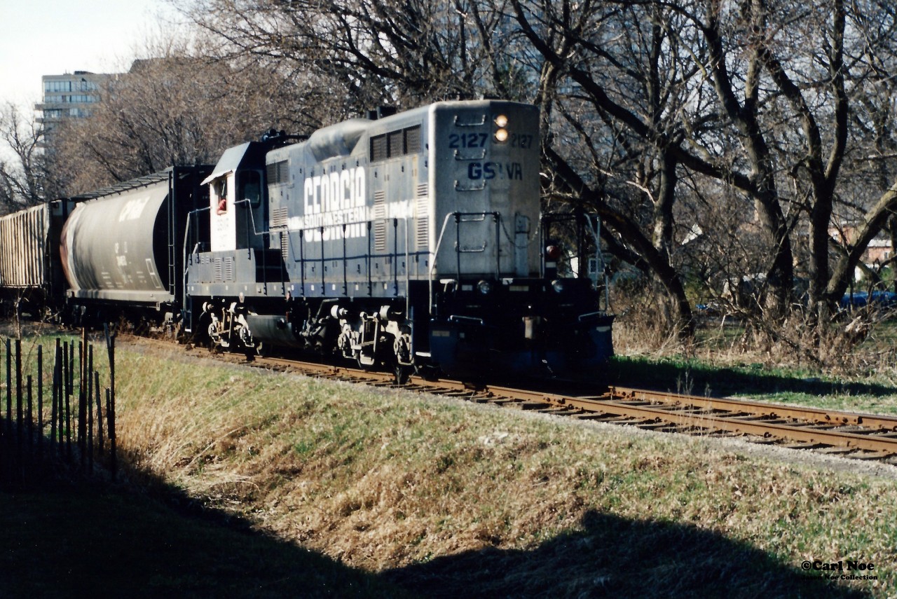During spring 1999 and less than one year after the Goderich-Exeter Railway (GEXR) had acquired the Guelph Subdivision and related spurs, units formally assigned to the Goderich Subdivision could be seen operating on the fairly still recently absorbed trackage.  

On April 8, 1999 word went out that Georgia Southwestern (GSWR) GP7u 2127 was assigned to train 582 and went north to Elmira during the afternoon on the Waterloo Spur. The former ATSF unit had certainly attracted a fair amount of attention and returned to Kitchener later in the early evening from Elmira.

Here GEXR 582 with GSWR 2127 is pictured slowly approaching the John Street crossing on the Waterloo Spur as it returns to Kitchener with three hoppers lifted from Nutrite Feeds in Elmira.