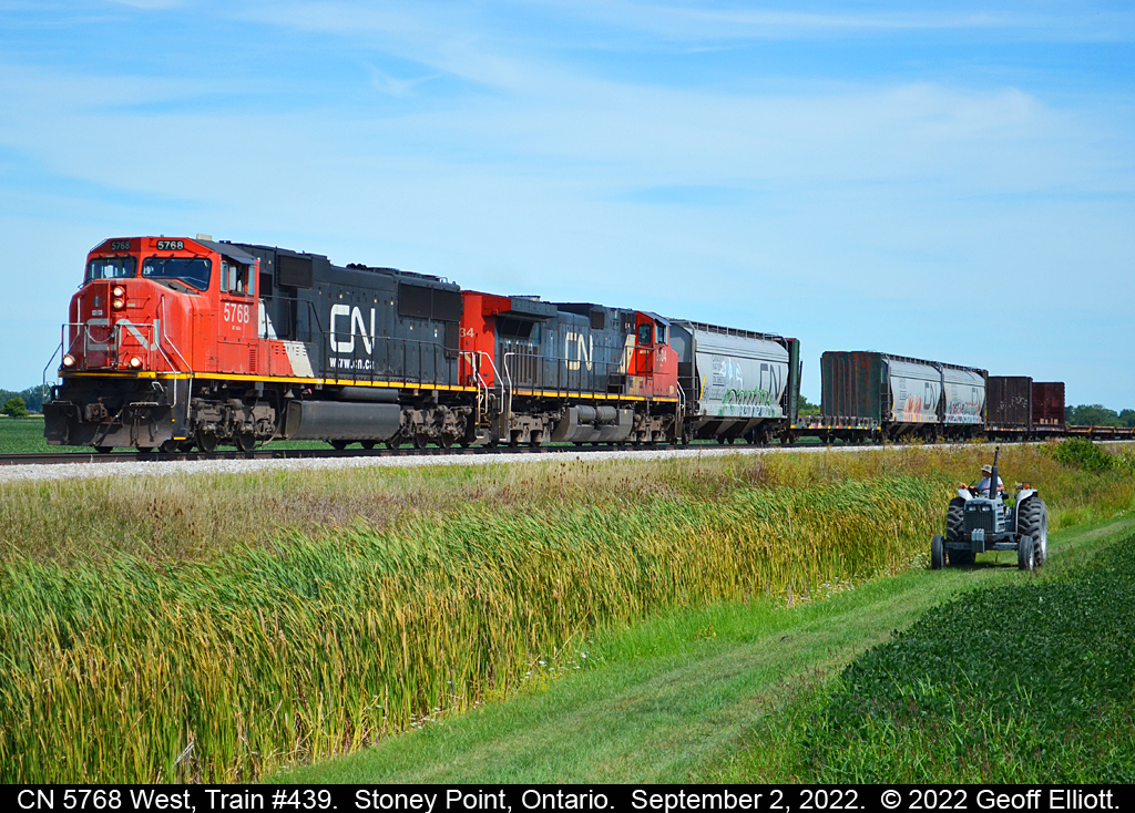CN Train #439 has left the siding in Stoney Point, Ontario after having met VIA #918, Train #76.  As CN 5768 starts to throttle up, Mr. Chauvin looks up to see the train pass as he cuts the weeds along the Right of Way with is trusty WHITE tractor.  Photo taken on Private Property with permission.