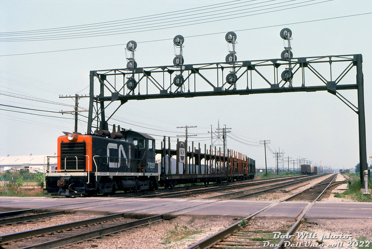 CN's Oakville Yard back in the day: CN SW1200 7020 works the west end of Oakville Yard, switching a cut of empty open autoracks over Chartwell Road grade crossing and under the signal bridge spanning the yard lead and CN's multi-track Oakville Subdivision mainline. Little GMD switchers like 7020 were kept busy by the nearby Oakville Ford Plant, that took a steady stream of boxcars full of auto parts inbound, and autoracks full of new automobiles outbound.

The CN 7000-series were "straight" SW9/SW1200 units not equipped with the roadswitcher package, like CN's 1200-1300 SW1200RS units were, but otherwise they were identical in horsepower. Note the relatively clean paint, single-beam "garbage can" headlight, AAR-A style switcher trucks, lack of MU plugs or cables, dual spark arrestors, and "flippity-flappity" rooftop radiator covers.

Bob Wilt photo, Dan Dell'Unto collection slide.