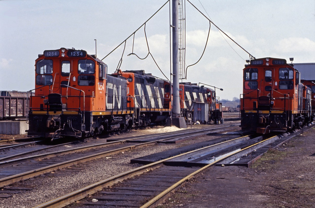 Back in 1990, Hamilton Yard was still a "going concern" operating 13 yard assignments on weekdays, while originating 5 wayfreights (555 to the Halton sub, 556, 557, and 558  to the Oakville sub, and 562 to the Grimsby sub), as well as Mac Yard turn 444 and 725 to Nanticoke. Power for some yard assignments--normally SW1200RS units by this time--was kept in the North Yard (or Parkdale for assignments starting there) while other yard and wayfreight engines (GP9s or GP9RMs) were kept at the Diesel Shop. Train 419 handled Sarnia traffic, train 333 took Black Rock (Buffalo) cars while 332 brought cars from the U.S., with trains 448 and 449 taking traffic between Niagara Falls and MacMillan Yard. With that for context, we see SW1200RSs 1254, 1289, and another "pup" as well as GP9 4371 (built as the 4112) and 4107 (rebuilt from the 4378, originally 4123) awaiting their next assignments at the Hamilton Yard diesel shop in the spring of 1990. [Train information from a January 1990 CN assignments document.)