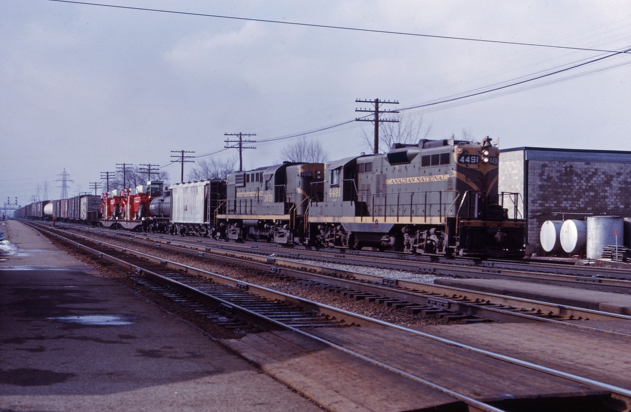 There's only a little snow on the ground here in Burlington in early 1966 as an eastbound freight starts up the Halton sub behind CN GP9 4491 and RS18 3659. While these units haven't been repainted, the new image is now starting to show up on some cars in the consist and many locomotives.