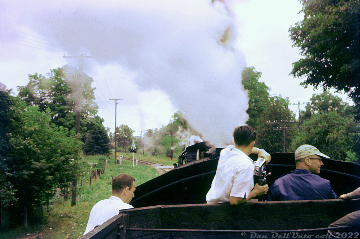 "Cab rides" on a steam engine? Normal back in 1959: some railfans participating on a Buffalo NRHS chapter fantrip over Canadian Pacific in southern Ontario are treated to an up-close experience of the signs, sounds and smells of steam, seen here riding the tender and cab area of CP D10h 1092 as her and sister 1098 head north out of Orangeville to wye their train at Fraxa Junction. Upon wying, the train will head back down the Owen Sound Sub to Orangeville in preparation for the trip back down the Orangeville Sub to Streetsville Junction. It's hard to pin down the exact location, but the train appears to be approaching Centre Street crossing near the north end of town, with a few trackside onlookers in the distance. Today, even if one was able to find operating steam, they would be hard-pressed to climb aboard a tender for a ride due to the usual legal liabilities.Original photographer unknown, Dan Dell'Unto collection slide (with quite a bit of work trying to colour correct this badly faded Ektachrome).