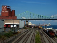 The Pointe St-Charles Switcher is leaving the Port of Montreal with a short train. In the background is the Jacques-Cartier bridge.