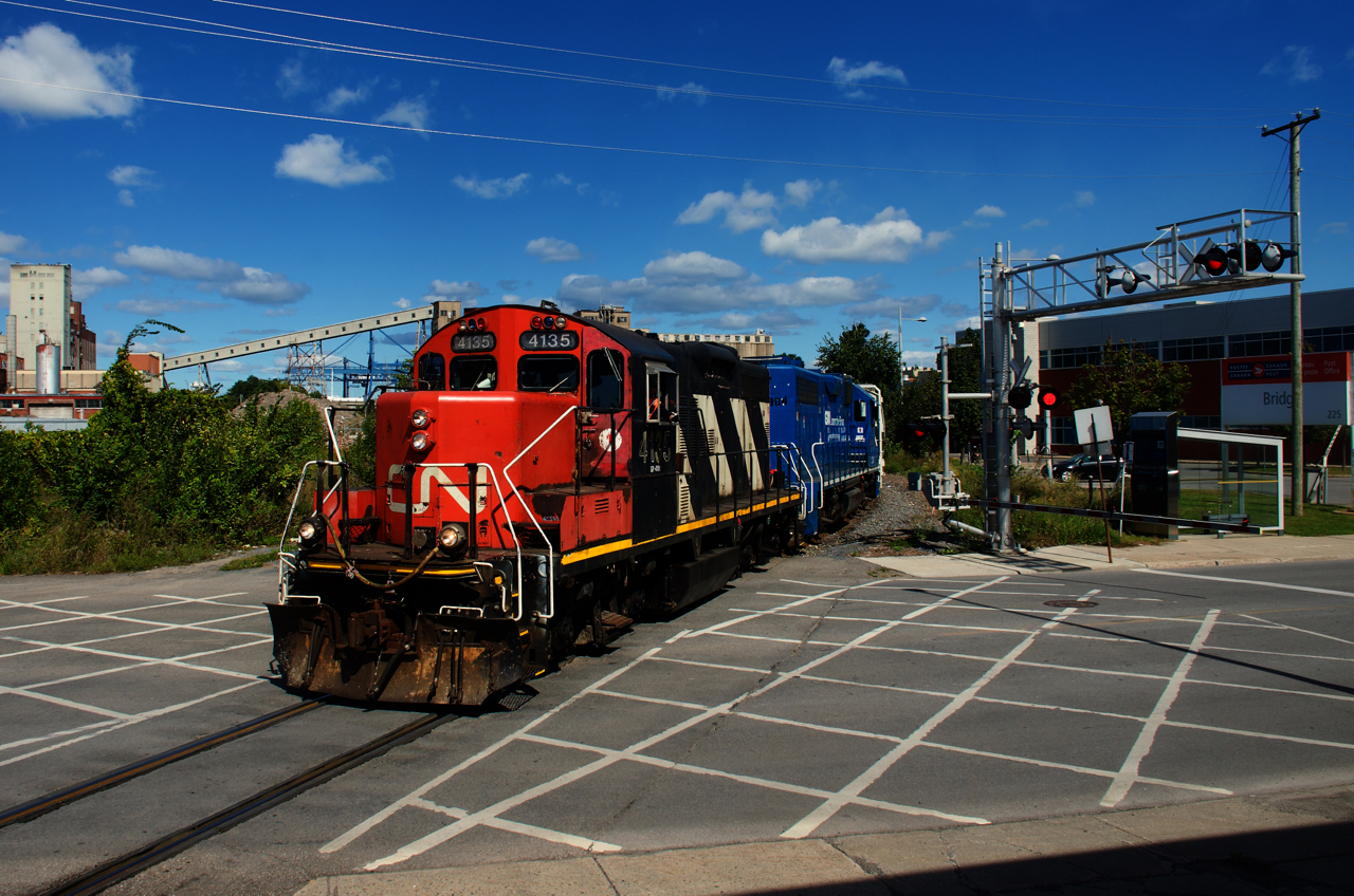 CN 4135 & CN 4904 are crossing Bridge Street with cars received in interchange from the Port of Montreal.