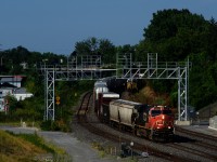 After spending the night tied down at Lachine, CN 306 is heading east with a fresh crew onboard. In the distance at right, CN 310's conductor gets back on the leading unit after they finished setting off cars on the Transfer Track.