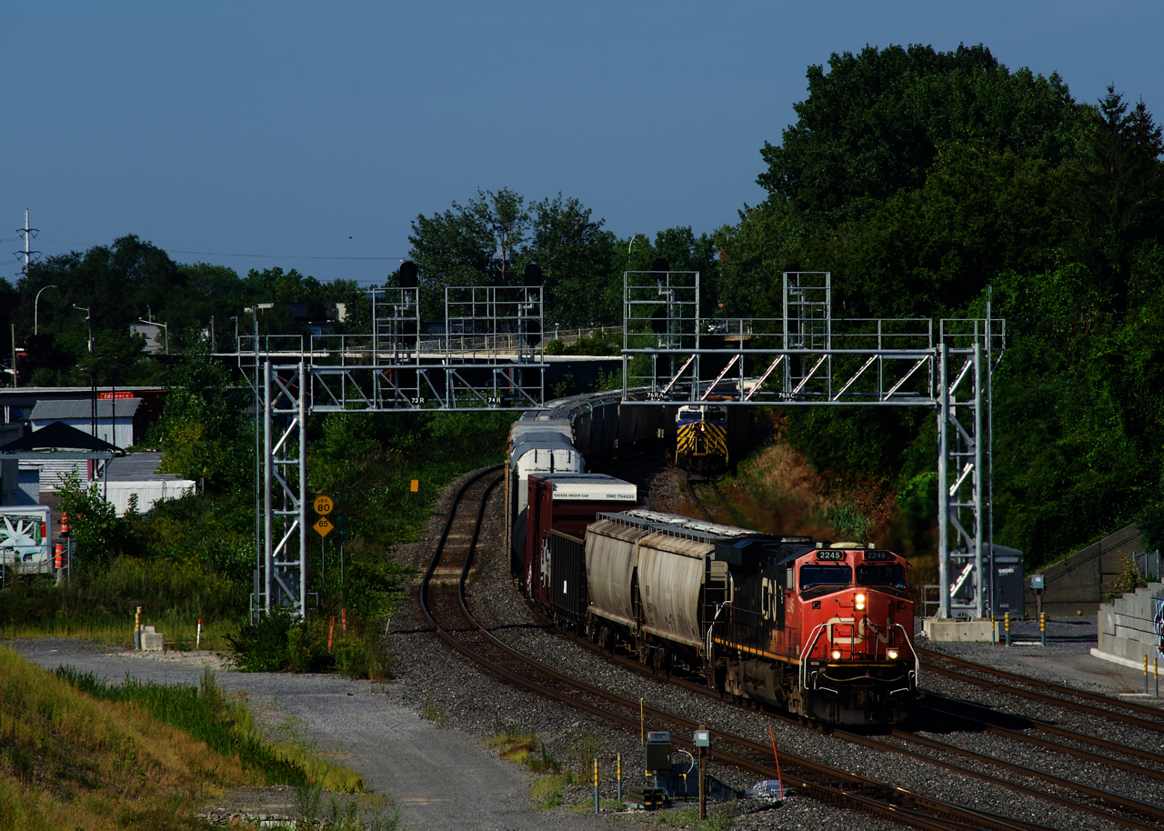 After spending the night tied down at Lachine, CN 306 is heading east with a fresh crew onboard. In the distance at right, CN 310's conductor gets back on the leading unit after they finished setting off cars on the Transfer Track.