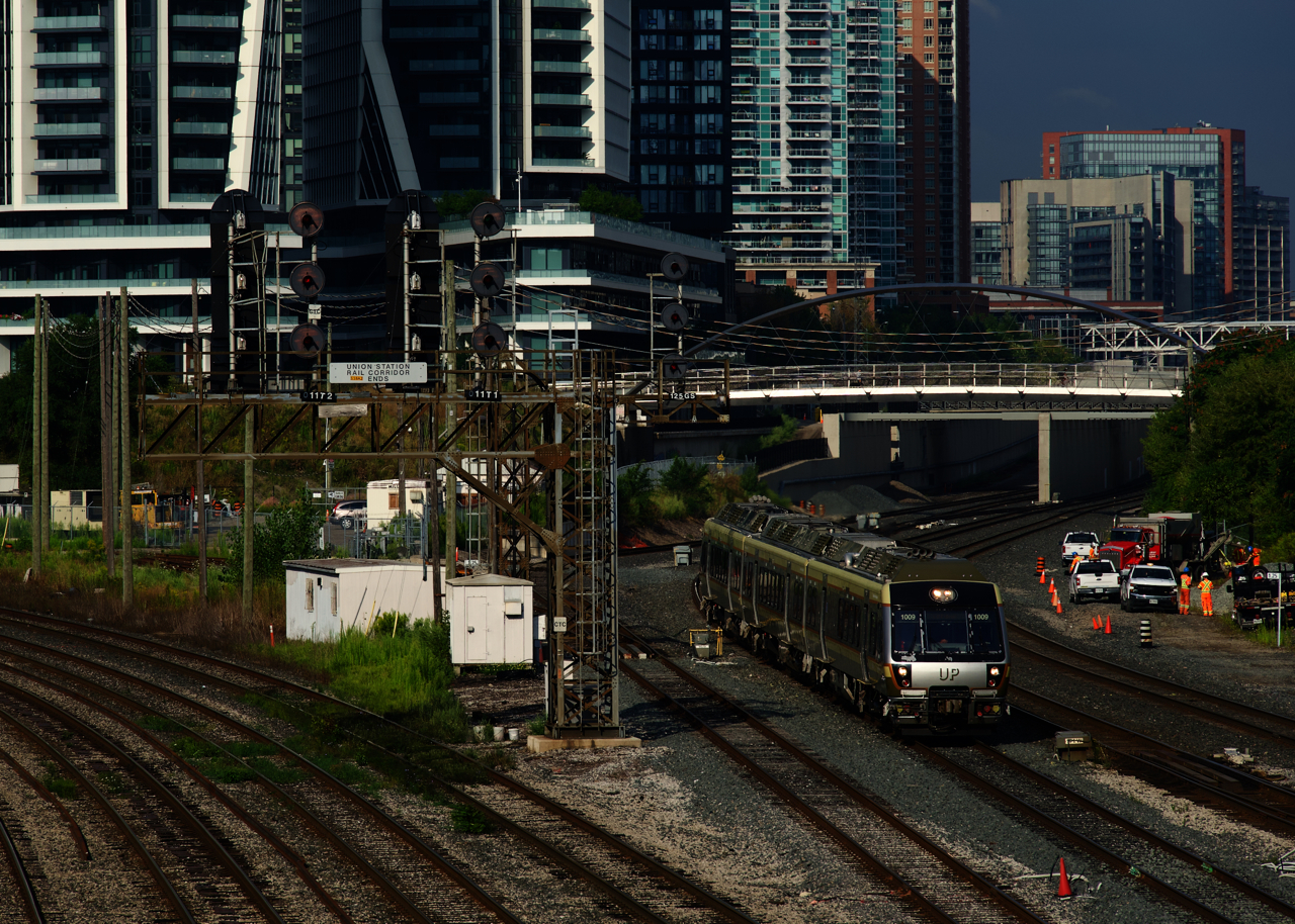 A Union Pearson Express train is passing a trio of searchlight signals, the middle one displaying a clear signal for a westbound.