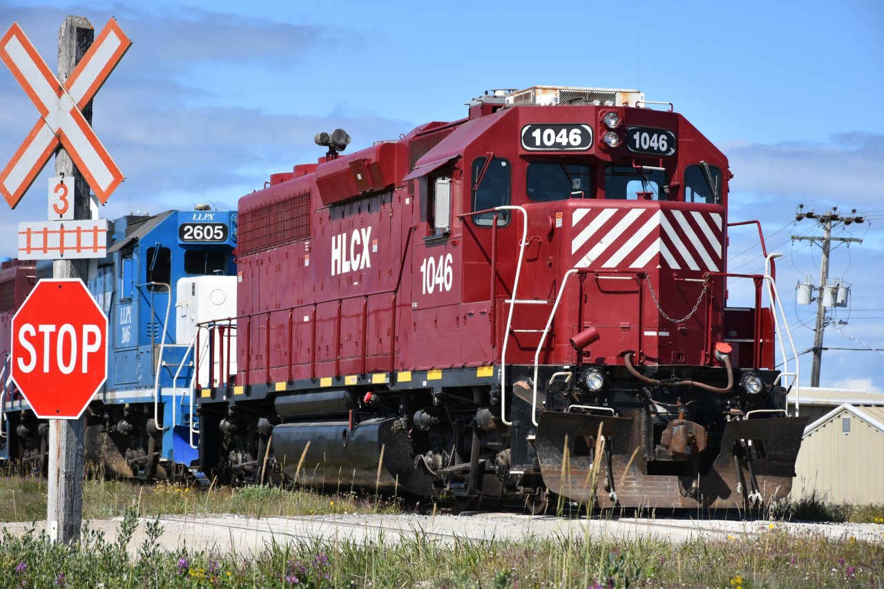 HLCX 1046 is the trailing unit of three on yard switching duty on this sunny afternoon in Churchill, MB. The trio of units is making a reverse move after running around a cut of cars on the grain dumper lead north of the station.