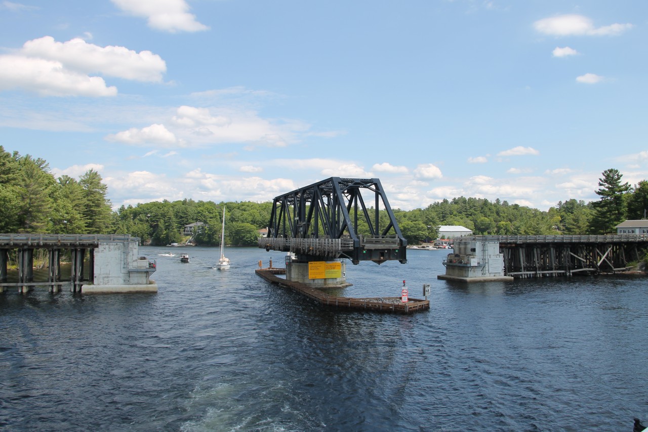The Island Queen is navigating the South Channel between Rose Point and Parry Island and has just passed the former Canadian National Railways swing bridge at Mile 4.9 Depot Harbor Subdivision. The bridge commonly known as the "Rose Point Swing Bridge" was built by the Ottawa, Arnpior and Parry Sound Railway in 1912, the bridge no longer carries rail traffic. Known officially as the Wasauksing Swing Bridge the bridge is owned by the Canadian Government and provides the only road access to Parry Island. Studies to replace the present structure have been underway for several years.