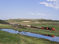 An eastbound just out of the terminal at Biggar rolls through a coulee with the CP,s north main Wilkie Sub. on the ridge above