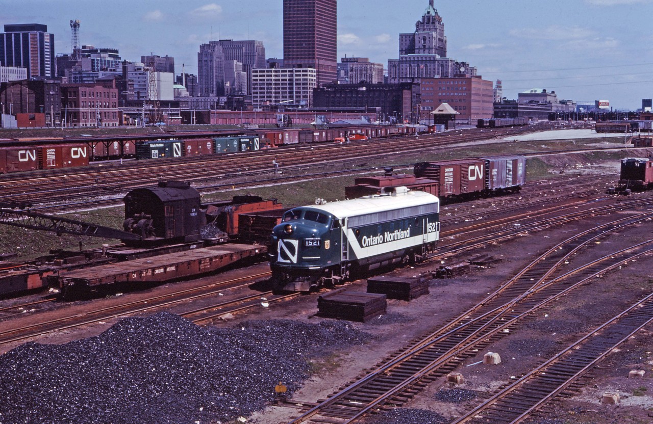 Ontario Northland 1521, one of three FP7s painted in the "Progressive" paint scheme (the others were 1502 and 1517), idles at CN's Spadina facilities in the spring of 1966. Note the steam powered crane, CN shed tracks, CN Express cars, CN Telecommunications Building (151 Front Street West), Front Street crossing leading to the CP Express Sheds, CP John Street piggyback facility (trailers), CP Royal York hotel, TTR John Street tower, and Union Station...looks a bit different today, eh?