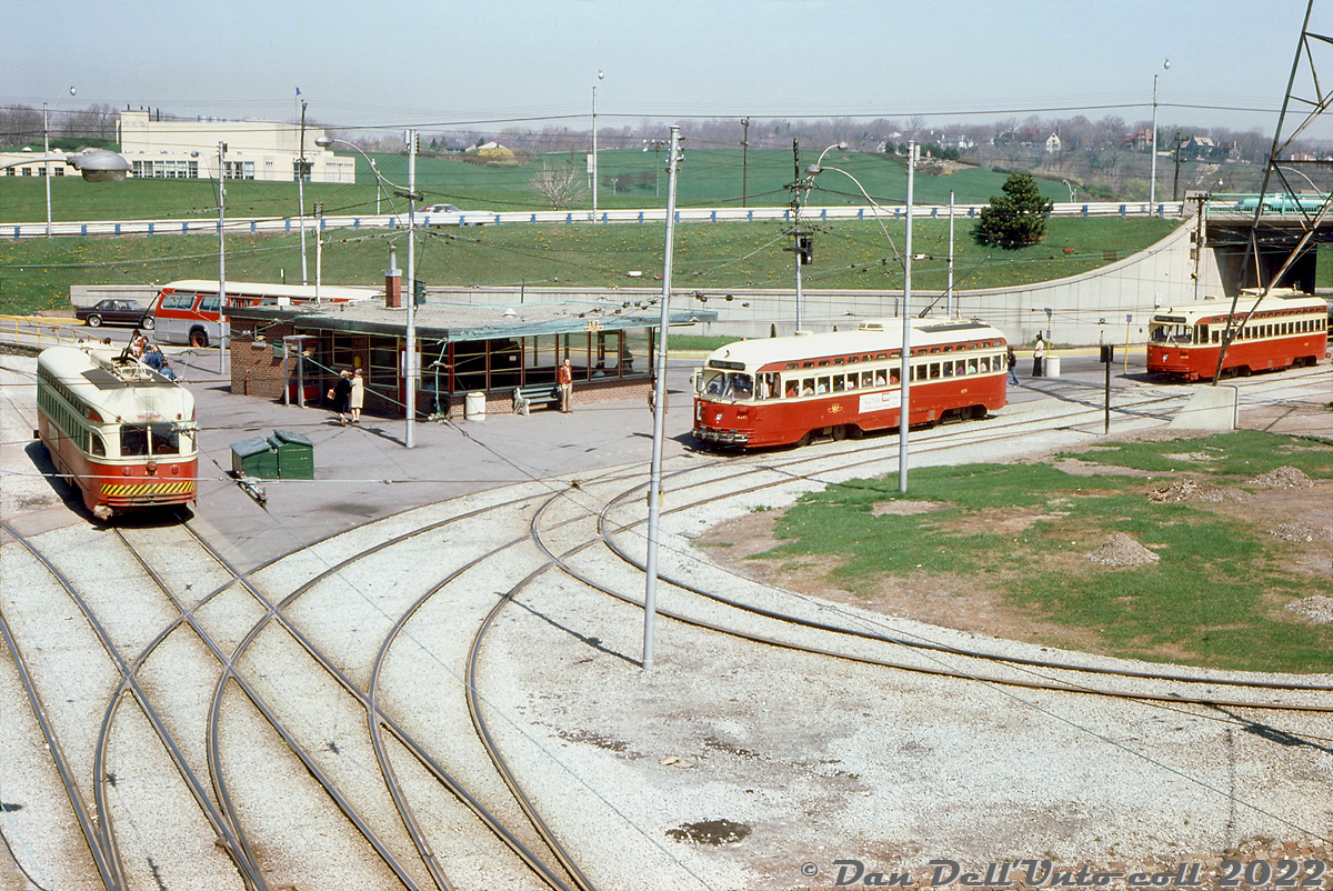It's a busy afternoon down at the TTC's Humber Loop, one of the two west-end terminuses of the Queen streetcar line, and long a notable interchange point between TTC streetcars and buses in southern Etobicoke. Here, TTC PCC 4391 (middle) takes on a load of passengers next to the waiting room building before beginning its trip back east along Queen to Neville Loop. Inbound 4426 (right) waits behind, and on the left another 4400-series car (4415?) sits on the other loop track for a trip further west to Long Branch Loop. A TTC GM "fishbowl" bus on a connecting route sits behind the waiting building in the bus loop. All of this is viewed from the embankment of CN's Oakville Sub to the south.

Original photographer unknown, Dan Dell'Unto collection slide.
