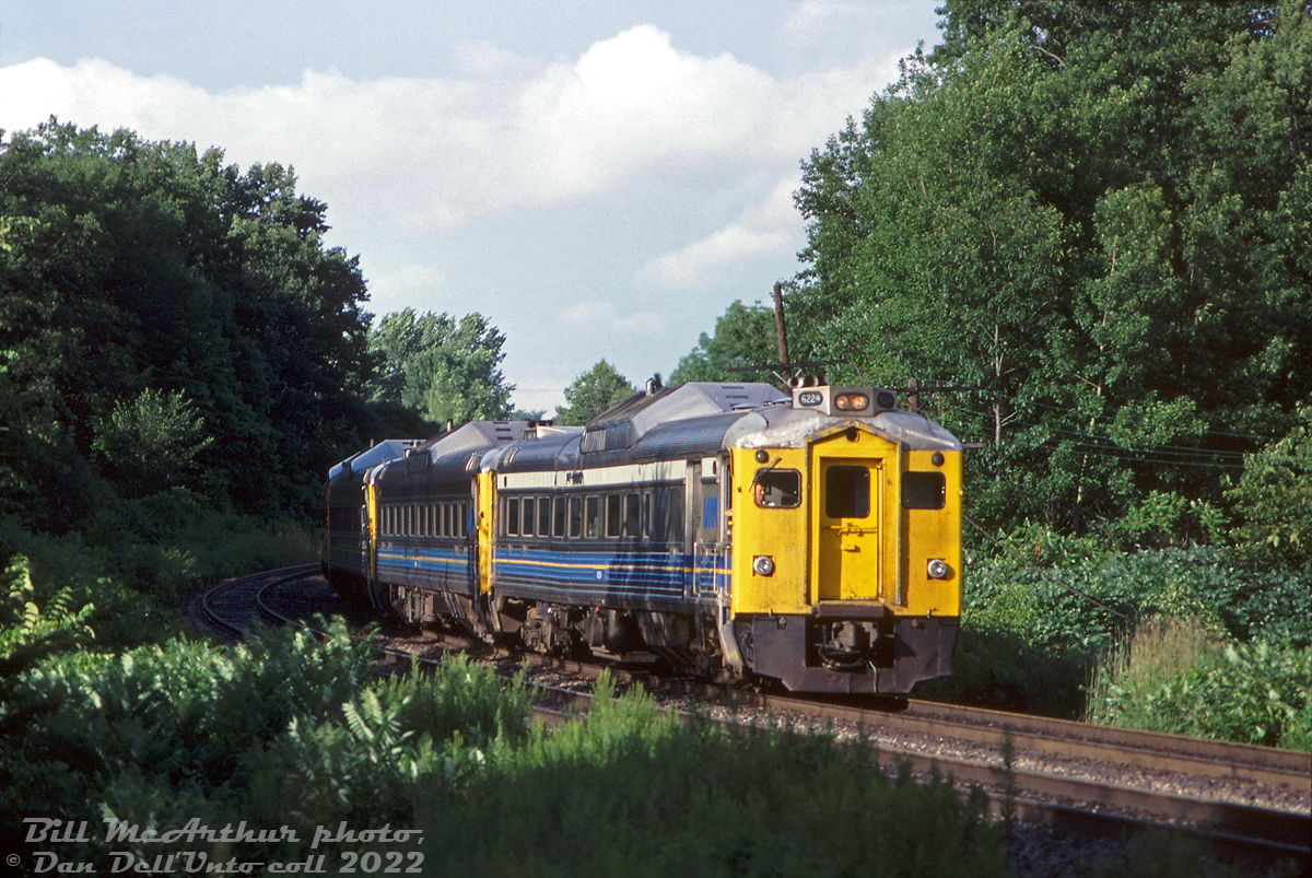 VIA RDC-2 6224 leads three other sister RDC's on a westbound passenger run near Bayview Junction, about to pass under Plains Rd. bridge. This is likely a Toronto-Niagara Falls train.

VIA 6224 has a bit of an interesting history, part of it evident in this photo. She was built as CP RDC-3 9023 by Budd in March 1955, later becoming part of VIA in September 1978. 9023 (still operating under CP colours for VIA) was wrecked at LaCombe AB in April 1980 (probably at a grade crossing accident while on the Calgary-Edmonton Budd run) and was repaired and repainted/renumbered as VIA 6357 by CN's Transcona Shops. 6357 didn't last long, as the unit was involved in another wreck at Balzac AB in August 1981, and this time Transcona repaired the car but also rebuilt it as RDC-2 6224 (a common conversion at the time that many VIA's RDC-3 units underwent: the RDC-2 featured more seating and a smaller baggage area). It was probably because of this latest accident that 6224 received its visibly noticeable carbody warping and sag, but the car soldiered on for VIA until retirement sometime in the 90's and was sold to Industrial Rail Services (IRSI) of Moncton NB in 2000. There it sat with many other RDC units as possible rebuild fodder, until IRSI experienced financial difficulties in the mid-2010's and most of the fleet was cut up for scrap metal. 6224 was finally cut up for scrap in January 2016.

Bill McArthur photo, Dan Dell'Unto collection slide.