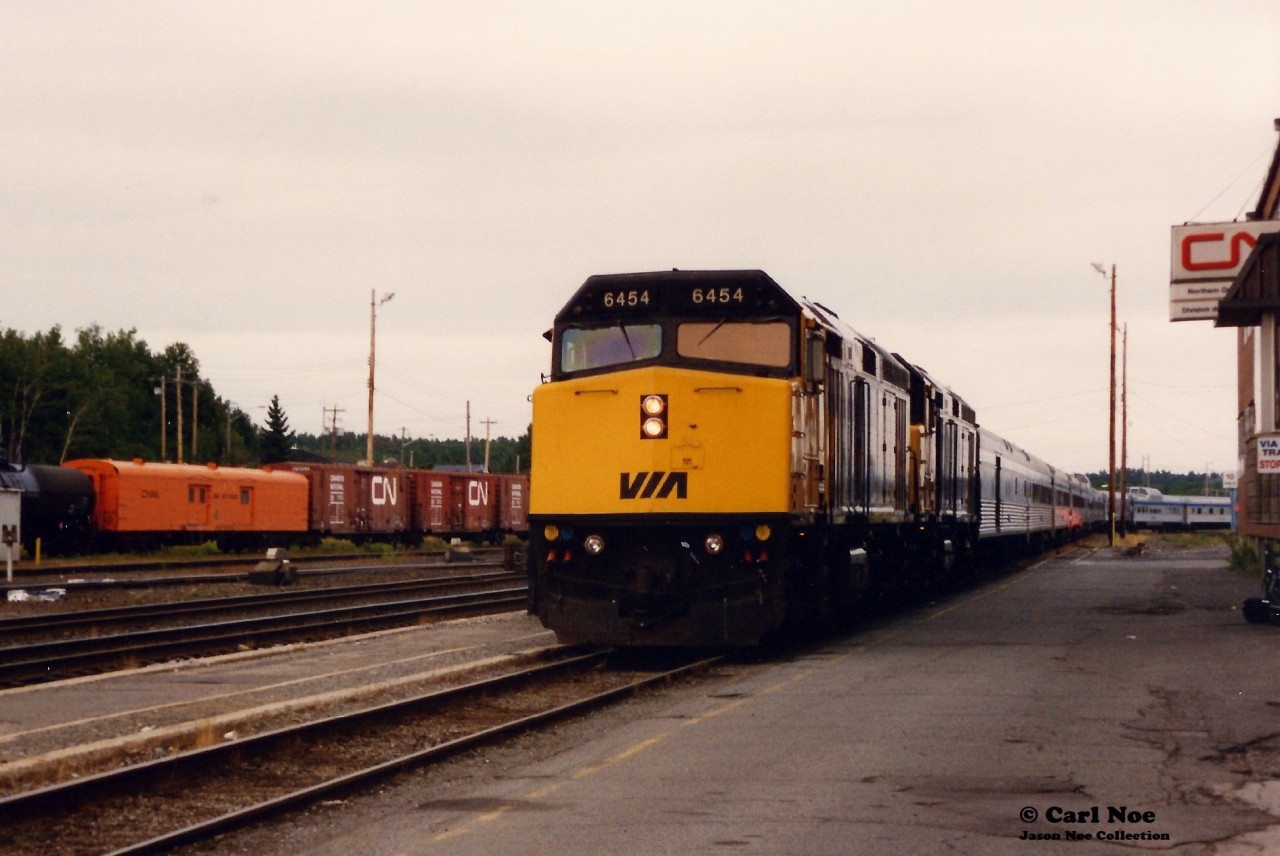 The westbound Canadian is viewed curving off the Bala Subdivision, arriving for its station stop in the town of Capreol passing the large CN building with 6454 and 6441.