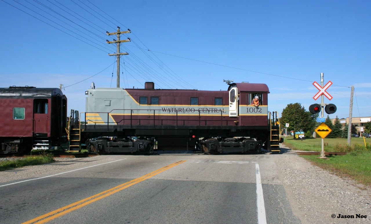 Following an extended hiatus due to the global pandemic, the first revenue Waterloo-Central Railway train to operate in over two years is viewed crossing King Street north of Waterloo, Ontario with S13 1002 leading towards St. Jacobs and Elmira.