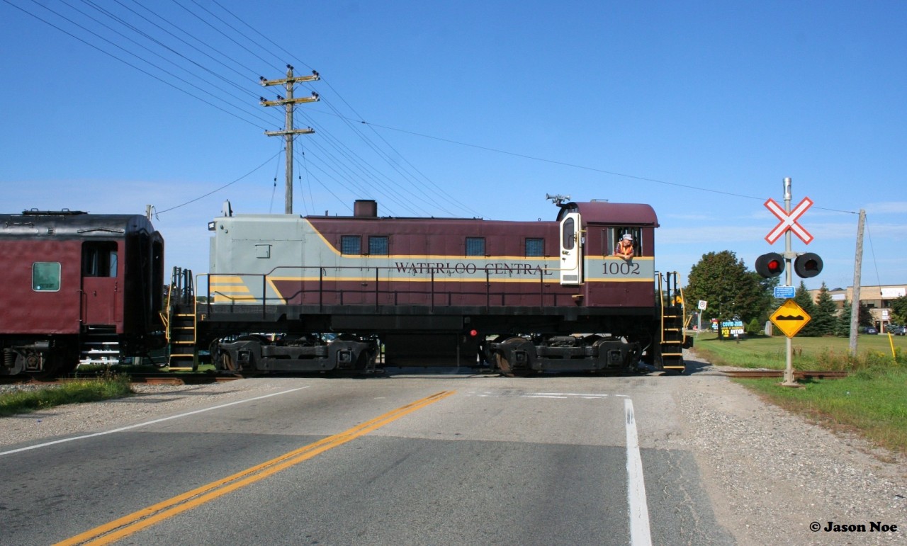 Following an extended hiatus due to the global pandemic, the first revenue Waterloo-Central Railway train to operate in over two years is viewed crossing King Street north of Waterloo, Ontario with S13 1002 leading towards St. Jacobs and Elmira.