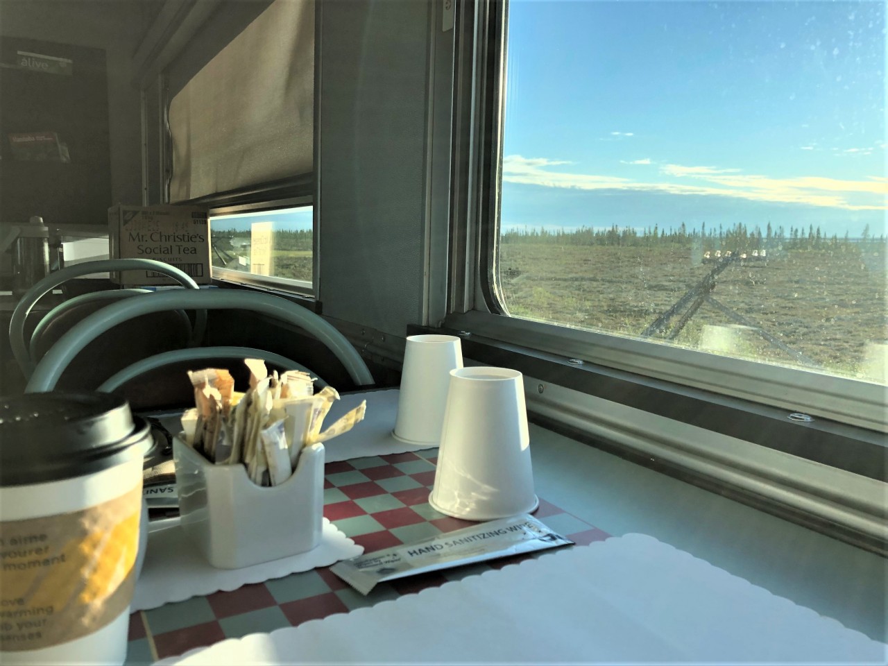 VIA #693 continues to roll north on the morning of August 2, 2022 getting ever closer to Churchill. After sitting in the Skyline dome sipping fresh made coffee and watching the sun rise for the passed hour & a half, I made my way down to the dining area of VIA 8515 Skyline to enjoy another cup of coffee and the smell of grilling bacon coming from the cars kitchen. It's now 06:48 and the train is around Mile 469.3 Chesnaye, MB, 2 hours & 10 minutes (40 miles) south of Churchill. I see the cars windows weren't cleaned overnight while I enjoyed a few hours sleep in VIA 8202 Chateau Bienville, but it didn't take away from the beautiful scenery outside as we rolled north. It almost looks like a wallpaper image covering the windows. Those tripod telegraph poles have dotted the trackside for many hundreds of miles of this great journey. In a few more minutes the VIA car attendant will be setting a plate full of scrambled eggs, bacon strips, hash browned potatoes, and fresh fruit slices in front of me for my final meal on this northbound run. Damn, retirement is great! :-)