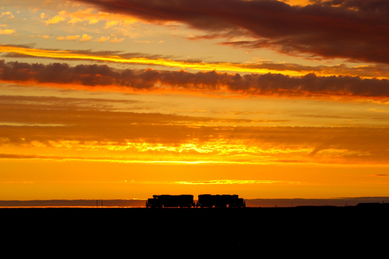 An often missed opportunity by many in their sleep is the share of good sunrises in the land of living skies. Here a pair of GP38s on the midnight yard job in Regina become a de-facto "locomotive henge" as sun beams diverge from the middle of the pairing whilst the patient crew waits for their next assignment.