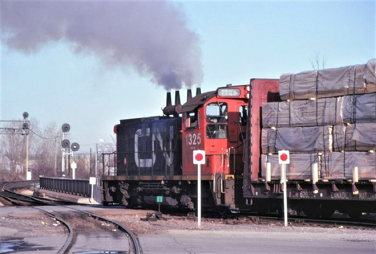 CN SW1200RS 1325 shoves hard on a cut of cars on a pleasant December 1982 afternoon.