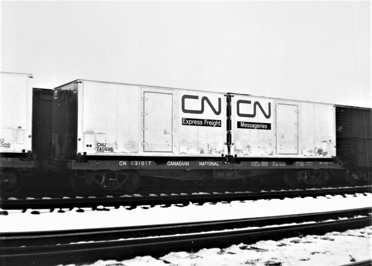 One of CN's early ventures into containerization were from rebuilt 40' outside braced boxcars. CN 631017 is shown in Capreol in January 1966 with a pair of express service containers.