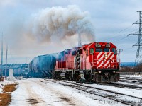 <i>"Throttle Eight, don't be late!</i> The engineer of this Thunder Bay yard job has unleashed all the horses of his two GP38-2's as the CP 3128 and CP 3029 struggle to lift a track of grain loads at "the Pocket", creating this spectacular scene, covering the intercity area in a cloud of diesel exhaust.